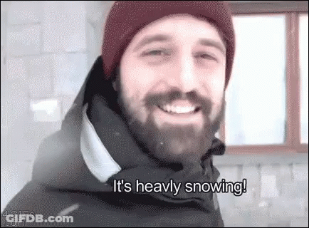Bearded Man In Hat And Jacket Smiling In Snow GIF
