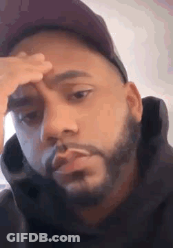 Bearded Man In Hat Holding Forehead Smoking Cigarette GIF