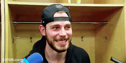 Bearded Man In Hat Holding Microphone In Locker Room GIF