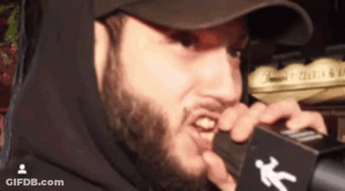 Bearded Man In Hat Holding Microphone In Mouth GIF