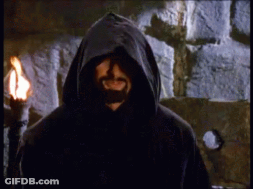 Bearded Man In Hood With Torch By Stone Wall GIF