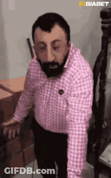 Bearded Man In Pink Shirt Standing With Boxes GIF