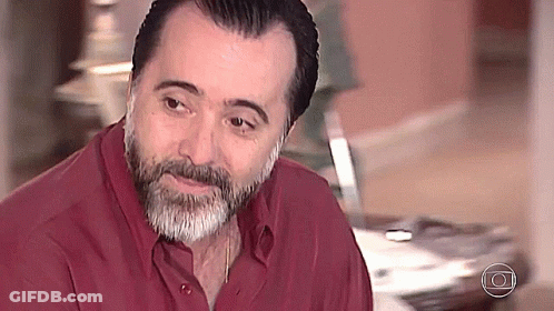 Bearded Man In Red Shirt Looking At Camera GIF