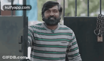 Bearded Man In Striped Shirt Smiling At Gate GIF