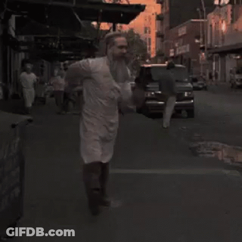 Bearded Man In White Apron Walking Down Street GIF