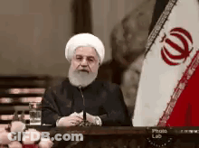 Bearded Man In White Hat At Table With Flag GIF