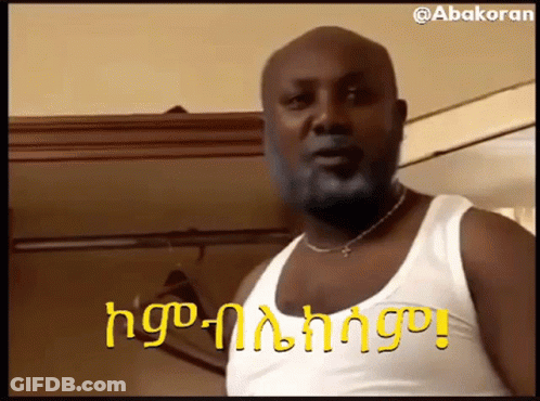 Bearded Man In White Tank Top And Necklace Beside Closet GIF