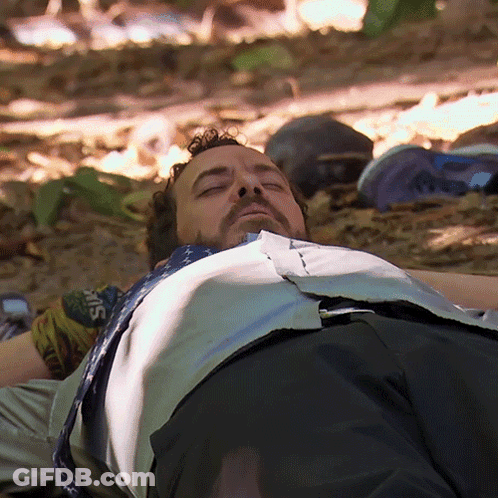 Bearded Man Laying On Ground Eyes Closed Shirt Saying Guns GIF