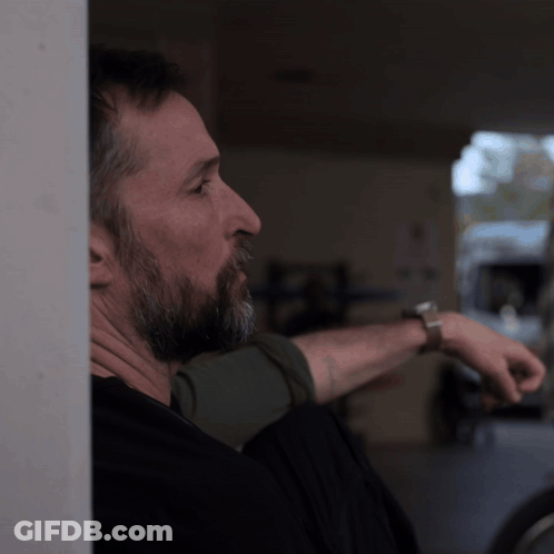 Bearded Man Leaning Against Wall Wearing Watch GIF
