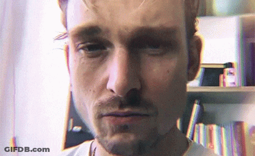 Bearded Man Looking At Camera Bookshelf GIF