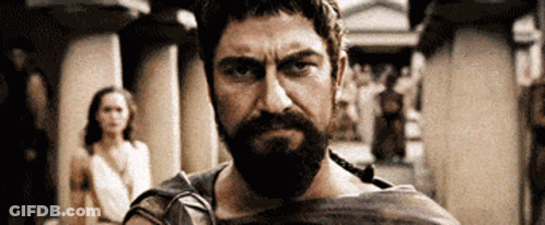 Bearded Man Looking At Camera With Woman In Background GIF