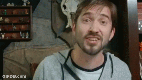 Bearded Man Making Funny Face In Front Of Shelf With Figurines GIF