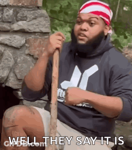 Bearded Man On Rock Holding Stick Says Well They Say It Is GIF