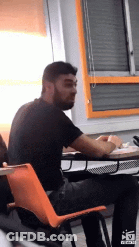 Bearded Man Sitting At Desk In Classroom GIF