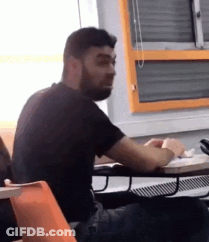 Bearded Man Sitting At Desk In Front Of Orange Window GIF