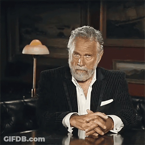 Bearded Man Sitting At Table With Folded Hands GIF