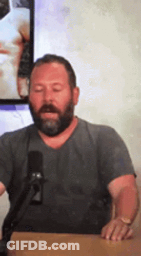 Bearded Man Sitting At Table With Microphone GIF