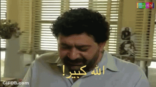 Bearded Man Sitting By Window With Arabic Writing GIF