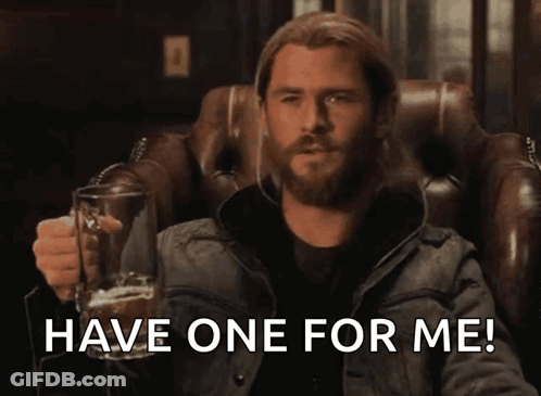 Bearded Man Sitting In Chair Holding Glass With Have One For Me GIF