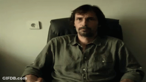 Bearded Man Sitting In Chair With Hands In Pockets GIF