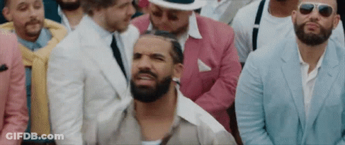Bearded Man Sitting In Crowd Of Suited Men With Sunglasses GIF