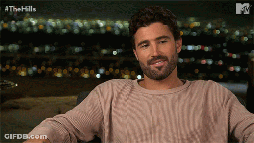 Bearded Man Sitting In Front Of City And Hills GIF
