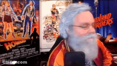 Bearded Man Sitting In Front Of Howard Movie Poster GIF