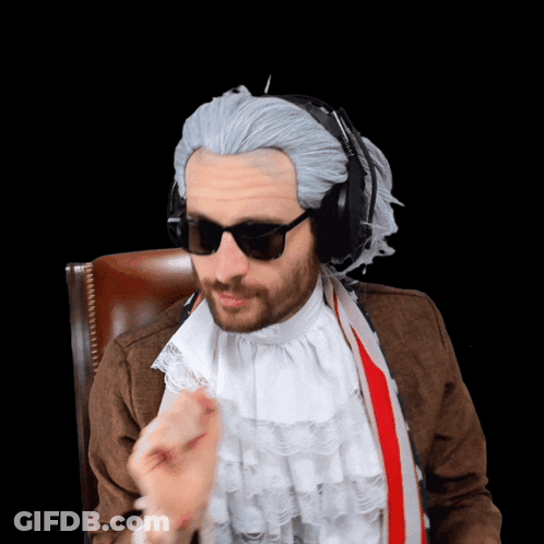Bearded Man Sitting On Bed Looking At Camera GIF