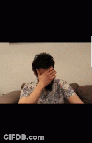Bearded Man Sitting On Couch With Hands On Face GIF