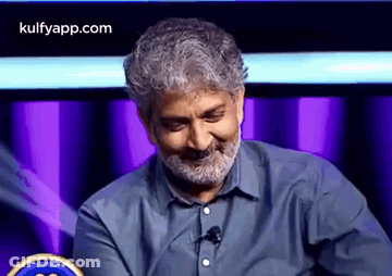 Bearded Man Smiling At Microphone On Stage GIF