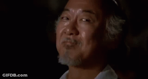 Bearded Man Smiling In Dark Room With Another Man GIF
