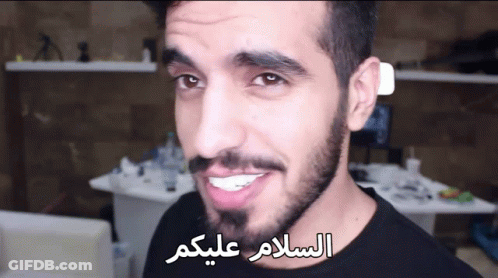 Bearded Man Smiling In Front Of Arabic Writing GIF