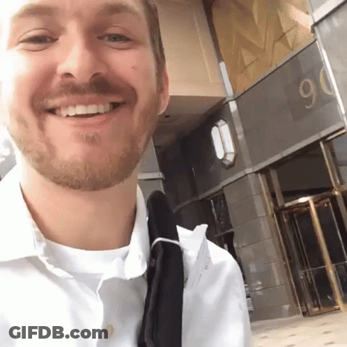 Bearded Man Smiling In Front Of Building Number 90 GIF