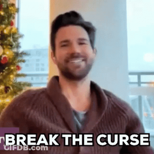 Bearded Man Smiling In Front Of Christmas Tree GIF