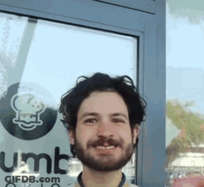 Bearded Man Smiling In Front Of Gumbo Sign GIF