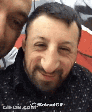 Bearded Man Smiling While Another Man Looks On GIF