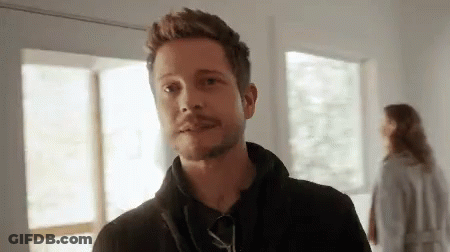 Bearded Man Standing With Woman In Background GIF