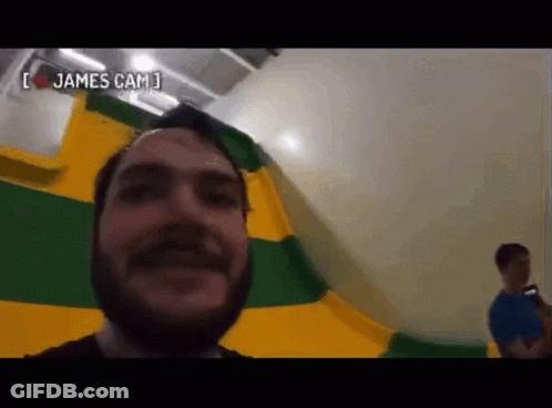 Bearded Man Taking Selfie In Front Of Yellow And Green Flag GIF