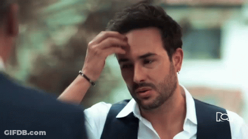 Bearded Man Touching Forehead With Blue Vest GIF