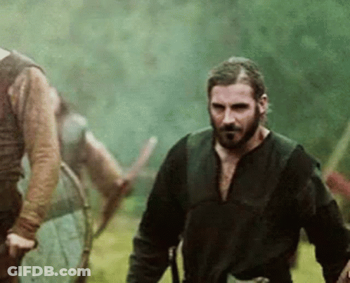 Bearded Man Walking With Sword In Field GIF