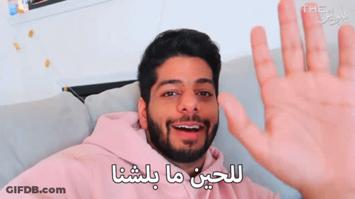 Bearded Man Waving Hand In Arabic On Couch GIF