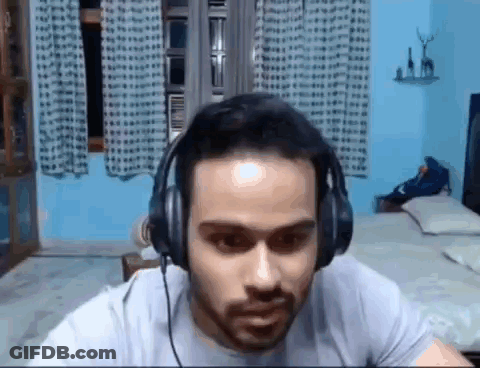 Bearded Man Wearing Headphones Sitting In Bedroom GIF