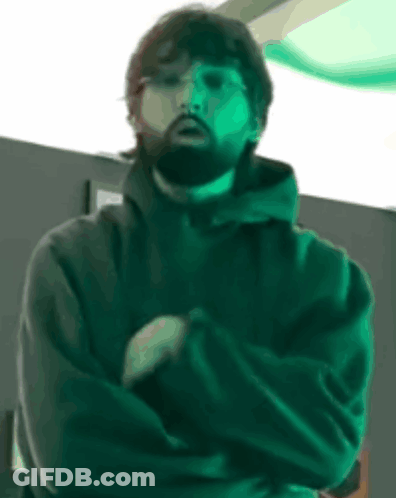 Bearded Man With Arms Crossed In Dark Room GIF