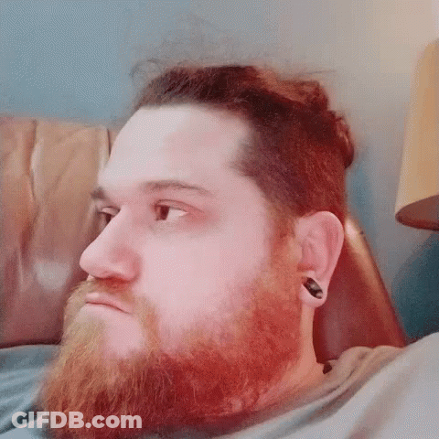 Bearded Man With Ear Plugs Laying On Couch GIF