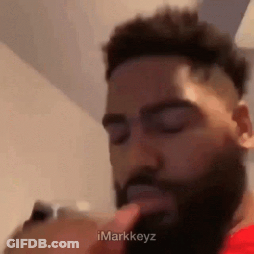 Bearded Man With Finger To Mouth Looking At Phone GIF