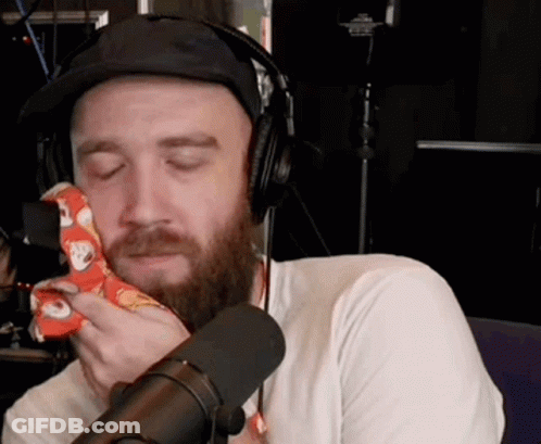 Bearded Man With Headphones And Hat Holding Napkin To Face GIF