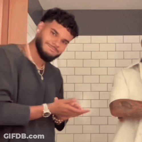 Bearded Man With Watch In Front Of White Brick Wall GIF