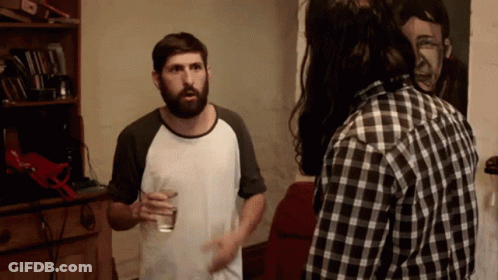 Bearded Man With Water Glass Talks To Plaid Shirt Man GIF