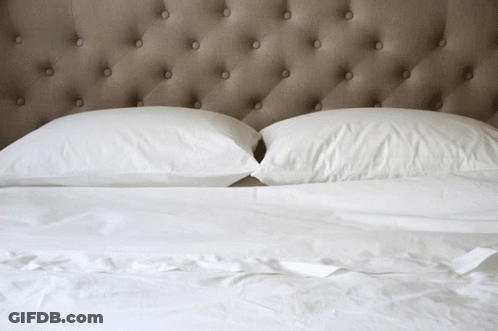 Bed With White Sheets Under Buttoned Headboard GIF
