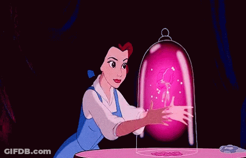 Belle From Beauty And The Beast Is Sitting At A Table With A Pink Flower Coming Out Of Her Hand . GIF